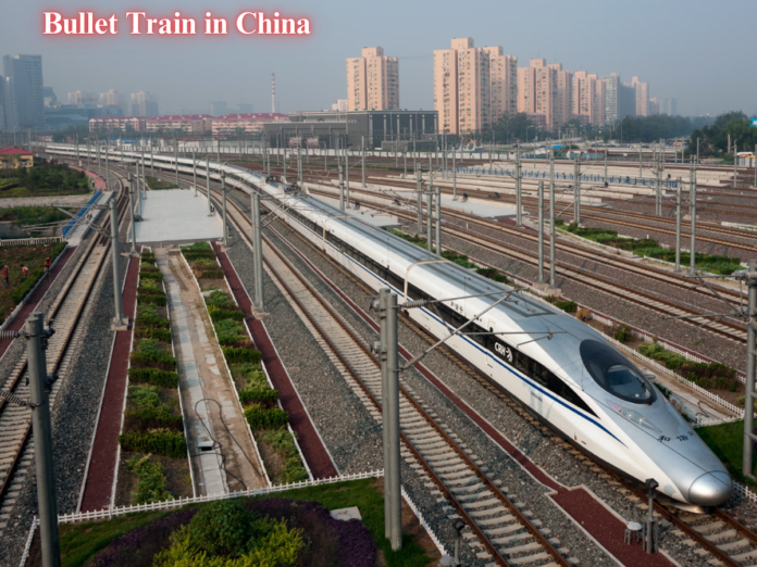 A modern bullet train in China traveling on a multi-track railway with tall buildings in the background.