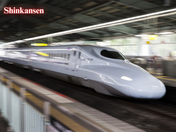 A Shinkansen bullet train speeding through a station.