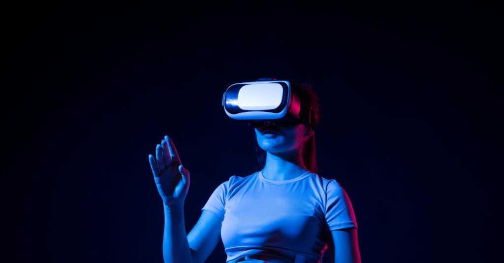 A person wearing a virtual reality headset, bathed in blue and pink lighting, extends a hand as if interacting with a virtual environment.